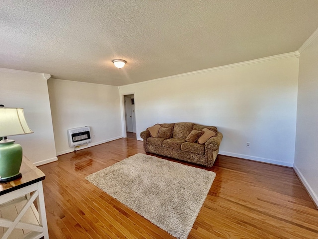 living room with heating unit, ornamental molding, a textured ceiling, wood finished floors, and baseboards