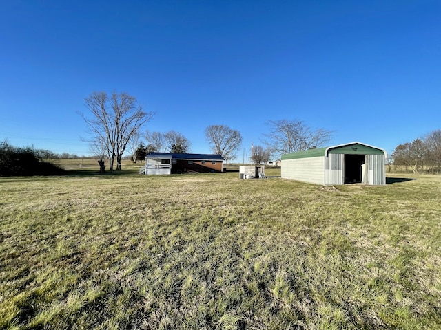 view of yard with a rural view, a pole building, and an outbuilding