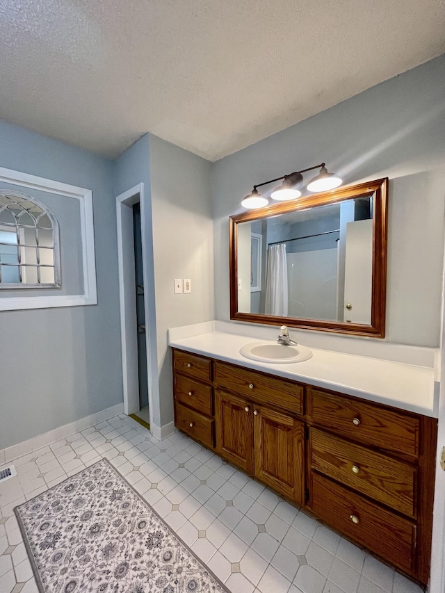 full bath featuring visible vents, baseboards, a shower with curtain, a textured ceiling, and vanity