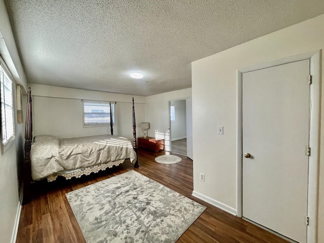 bedroom with a textured ceiling, baseboards, and dark wood-style flooring