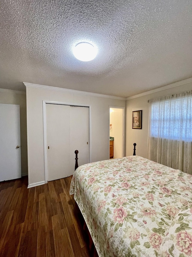 bedroom featuring a textured ceiling, ornamental molding, a closet, and dark wood finished floors