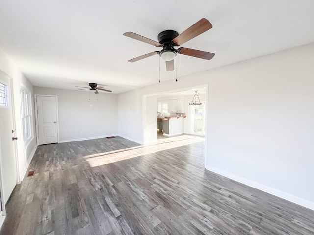 unfurnished living room with a ceiling fan, baseboards, and wood finished floors