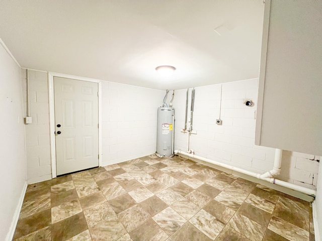 basement featuring concrete block wall and electric water heater