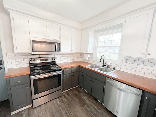 kitchen with stainless steel appliances, dark wood-style flooring, a sink, and gray cabinetry