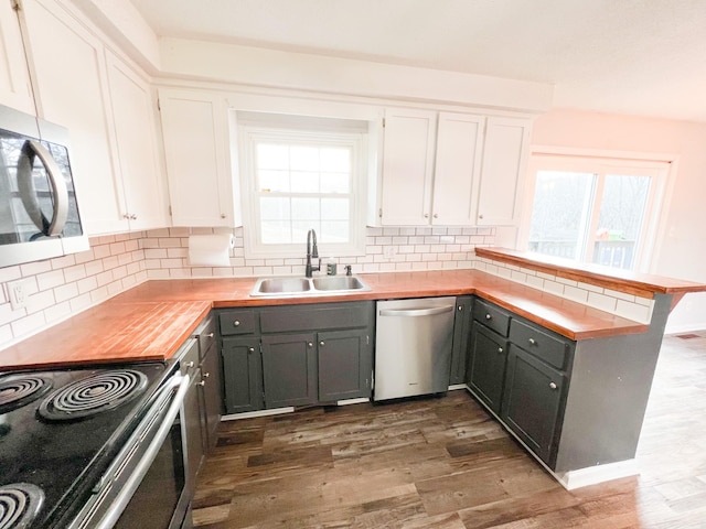 kitchen with white cabinets, a peninsula, gray cabinets, stainless steel appliances, and a sink