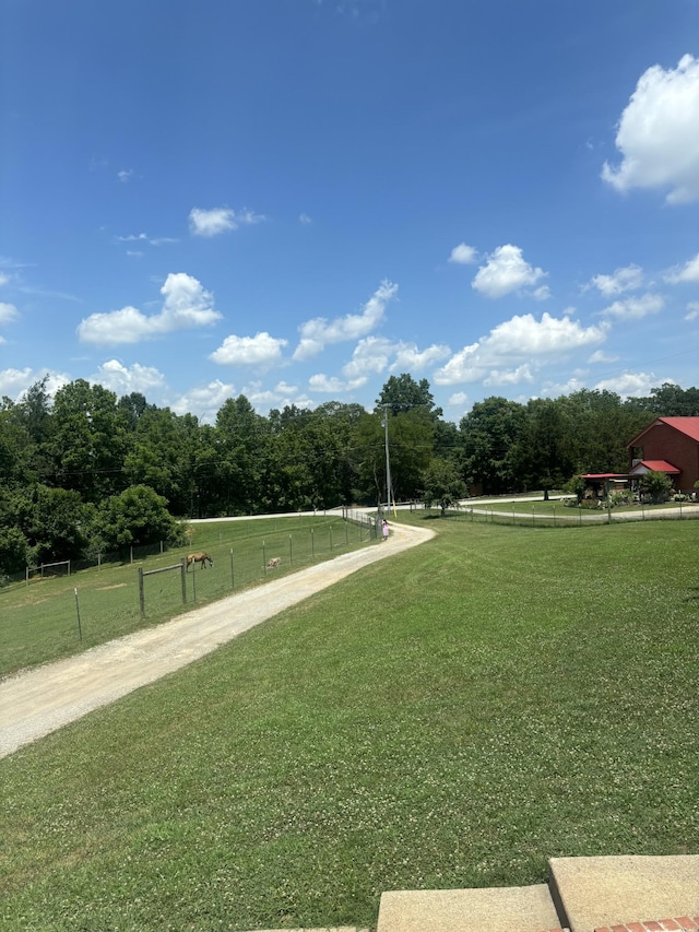 view of community featuring a yard, a rural view, a forest view, and fence