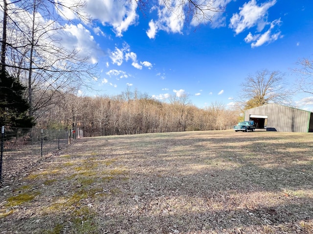 view of yard featuring a garage, a pole building, an outdoor structure, and fence