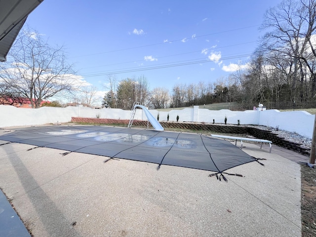 view of pool featuring a water slide, a fenced backyard, a diving board, a fenced in pool, and a patio area