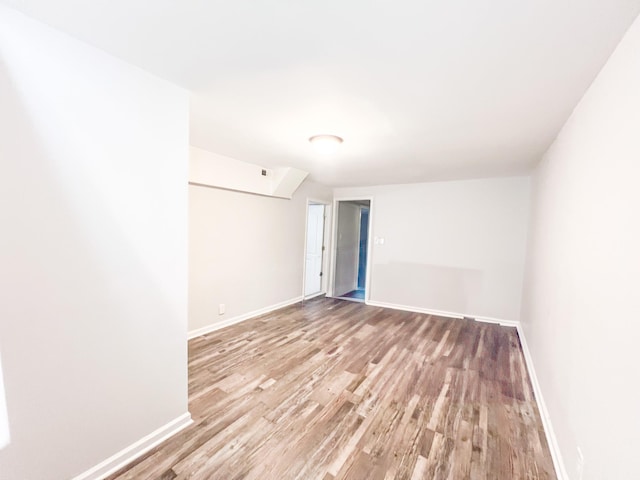 spare room featuring visible vents, baseboards, and wood finished floors