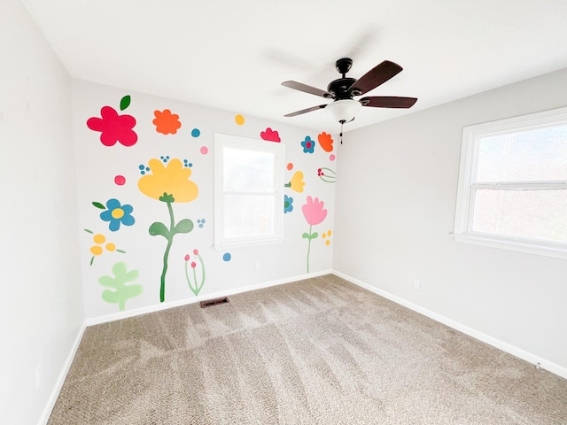 carpeted empty room featuring visible vents, ceiling fan, and baseboards