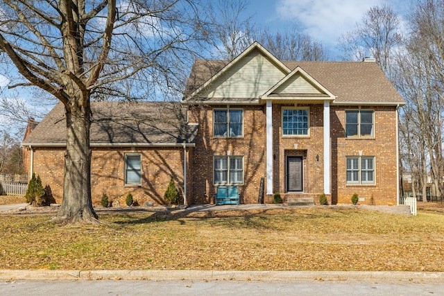 greek revival inspired property featuring roof with shingles, a chimney, and brick siding