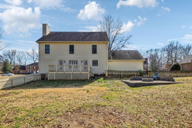 back of property featuring a chimney, a fenced backyard, a yard, and a deck