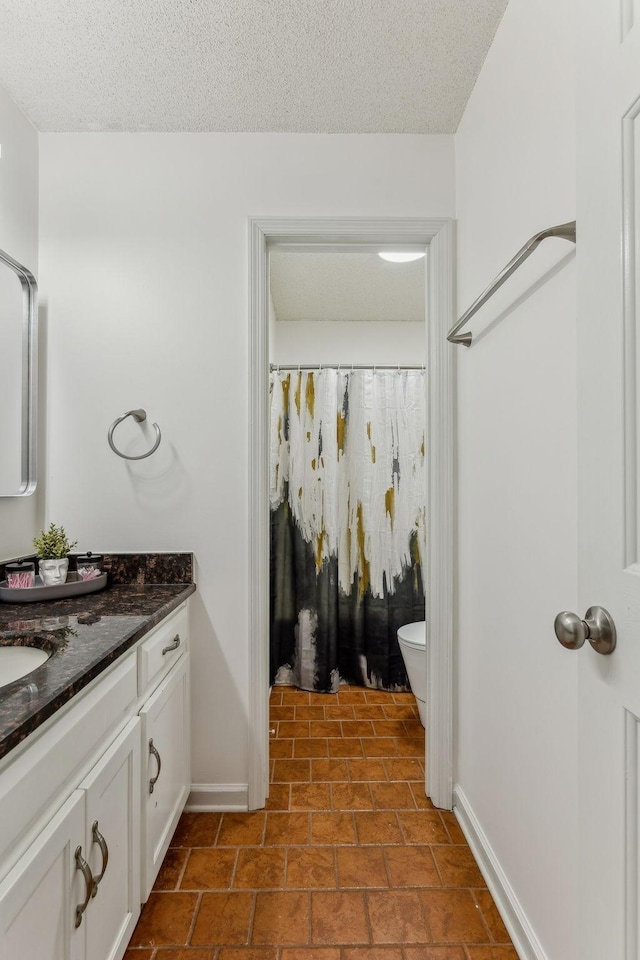 full bathroom with baseboards, vanity, toilet, and a textured ceiling