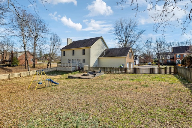 rear view of house with a playground, a yard, a chimney, and a fenced backyard