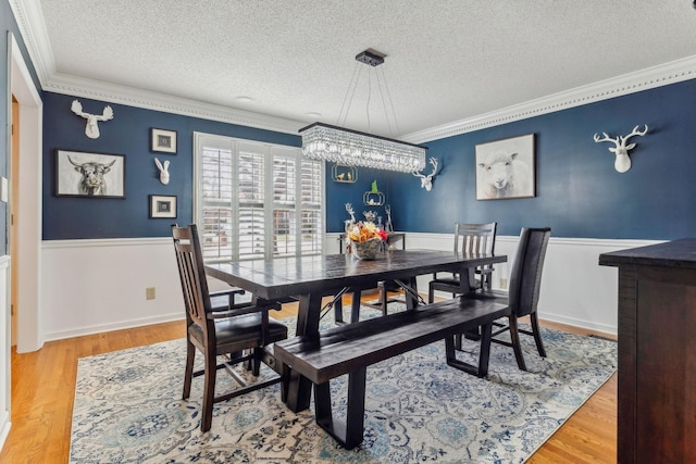 dining space featuring wainscoting, a textured ceiling, and wood finished floors