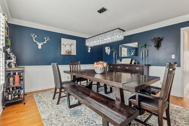 dining area featuring ornamental molding, a wainscoted wall, and wood finished floors