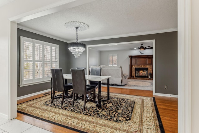 dining room featuring a fireplace, plenty of natural light, wood finished floors, and crown molding