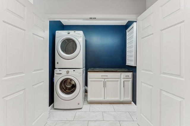 clothes washing area with stacked washer / drying machine and cabinet space