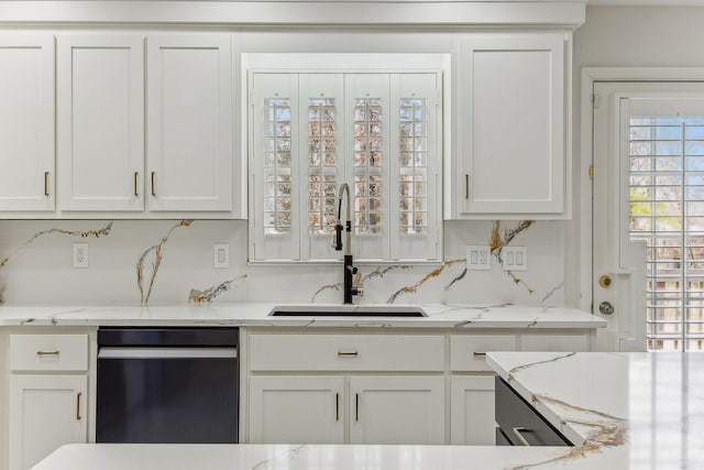 kitchen with dishwashing machine, white cabinets, and a sink