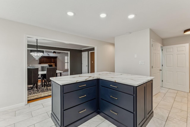 kitchen featuring recessed lighting, marble finish floor, a kitchen island, and light stone countertops