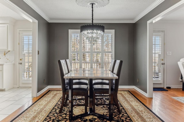 dining room with a wealth of natural light, a textured ceiling, light wood finished floors, and an inviting chandelier