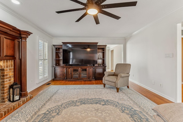 living area featuring baseboards, ceiling fan, wood finished floors, and crown molding