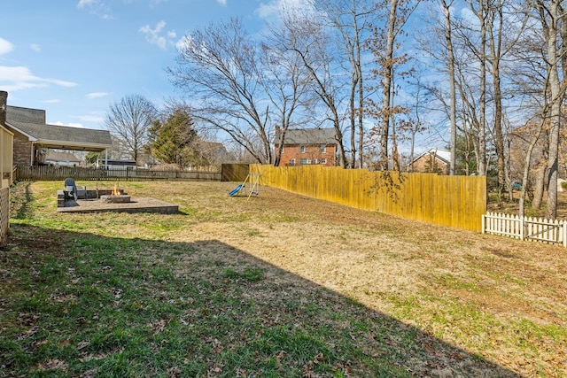 view of yard with an outdoor fire pit, a fenced backyard, and a playground