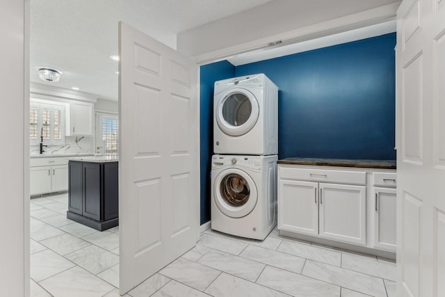 clothes washing area with stacked washer / drying machine, marble finish floor, and cabinet space