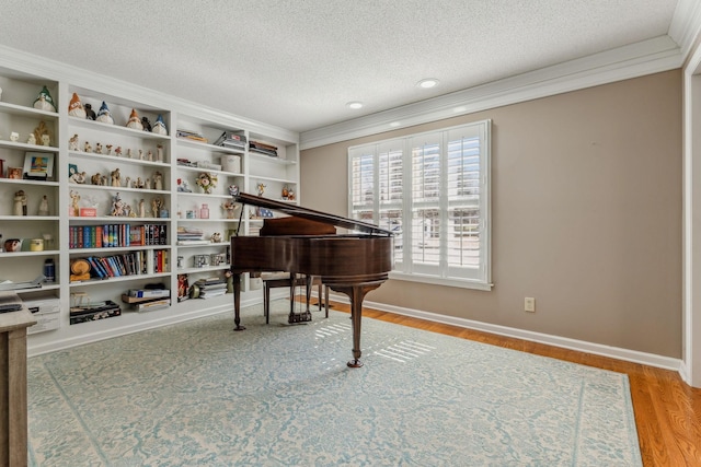 sitting room with a textured ceiling, baseboards, wood finished floors, and crown molding