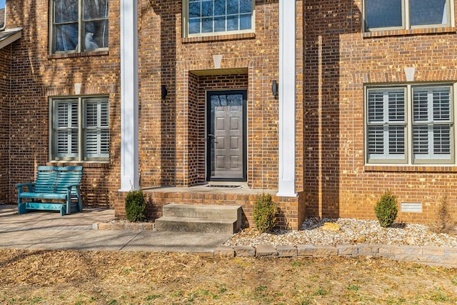 entrance to property featuring crawl space and brick siding