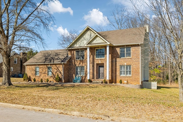 view of front of home with brick siding, a chimney, and a front lawn