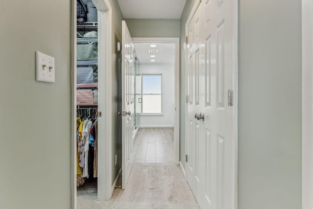 corridor with carpet, visible vents, and baseboards