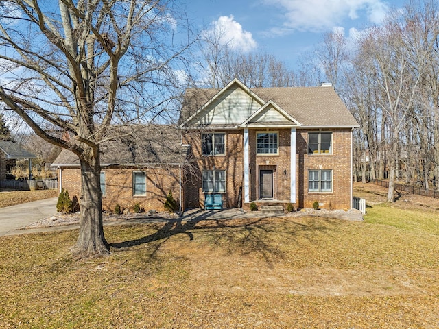 greek revival house featuring brick siding, a chimney, and a front yard