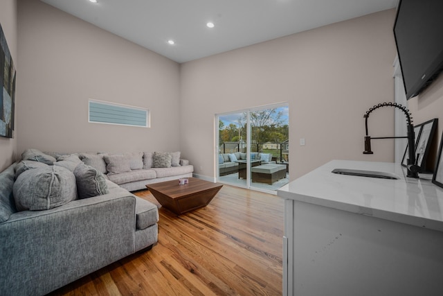 living room featuring a high ceiling, recessed lighting, and light wood-style floors