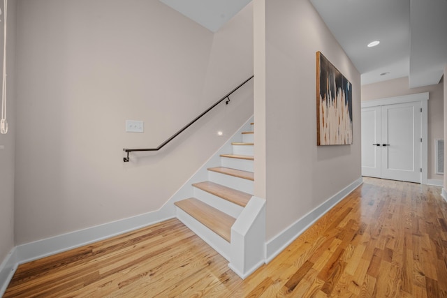 stairway with visible vents, baseboards, and wood finished floors