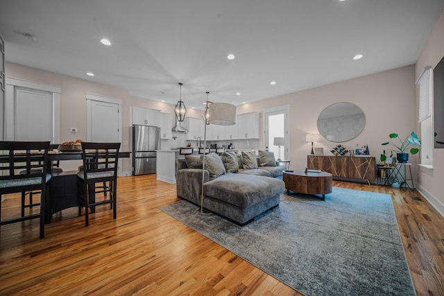 living area featuring light wood-type flooring, baseboards, and recessed lighting