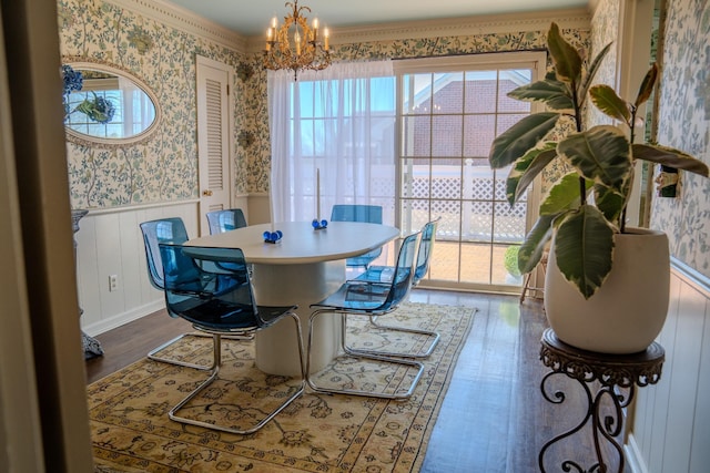 dining area featuring a wainscoted wall, a chandelier, wood finished floors, and wallpapered walls