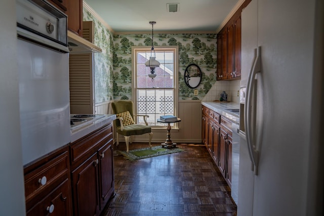 kitchen with white appliances, wallpapered walls, tile counters, visible vents, and pendant lighting