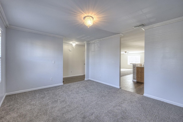 empty room featuring carpet floors, ornamental molding, visible vents, and baseboards