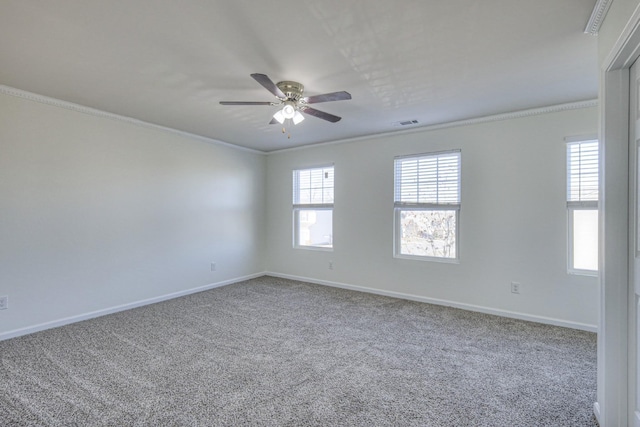 carpeted spare room with baseboards, visible vents, ornamental molding, and a ceiling fan