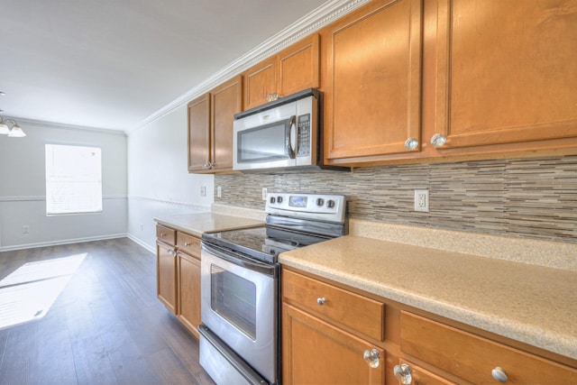 kitchen with crown molding, light countertops, decorative backsplash, appliances with stainless steel finishes, and brown cabinetry