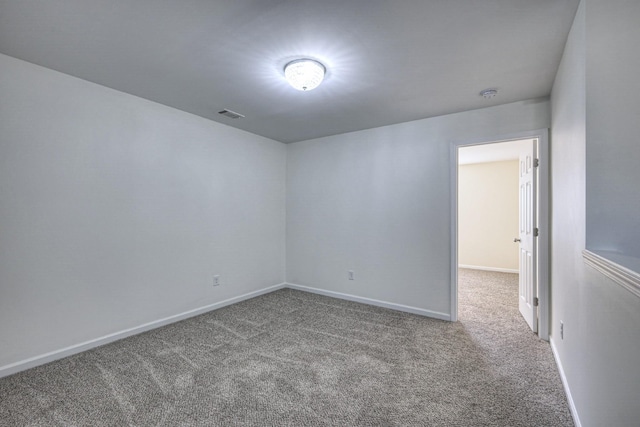 spare room with carpet floors, visible vents, and baseboards