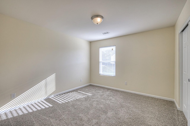 empty room featuring carpet, visible vents, and baseboards