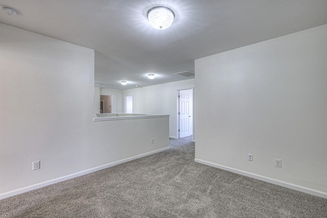 unfurnished room with carpet, visible vents, and baseboards