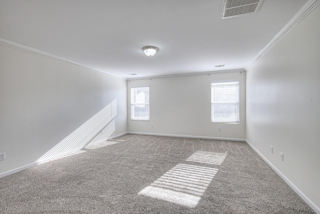 spare room with carpet, baseboards, visible vents, and crown molding