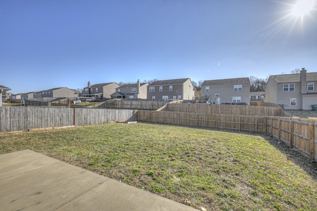 view of yard featuring a patio area, a fenced backyard, and a residential view