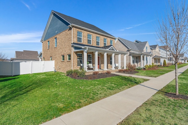 view of front of property with a front yard, covered porch, brick siding, and fence