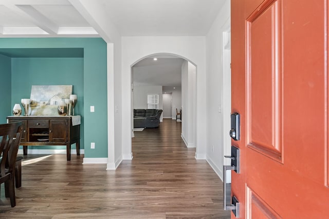 foyer featuring dark wood-style floors, arched walkways, and baseboards