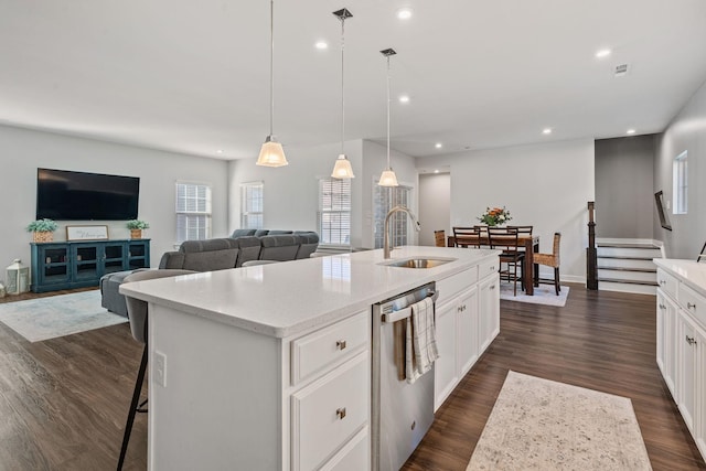 kitchen with dark wood finished floors, recessed lighting, a sink, an island with sink, and dishwasher