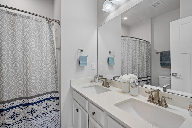 bathroom featuring visible vents, a sink, toilet, and double vanity